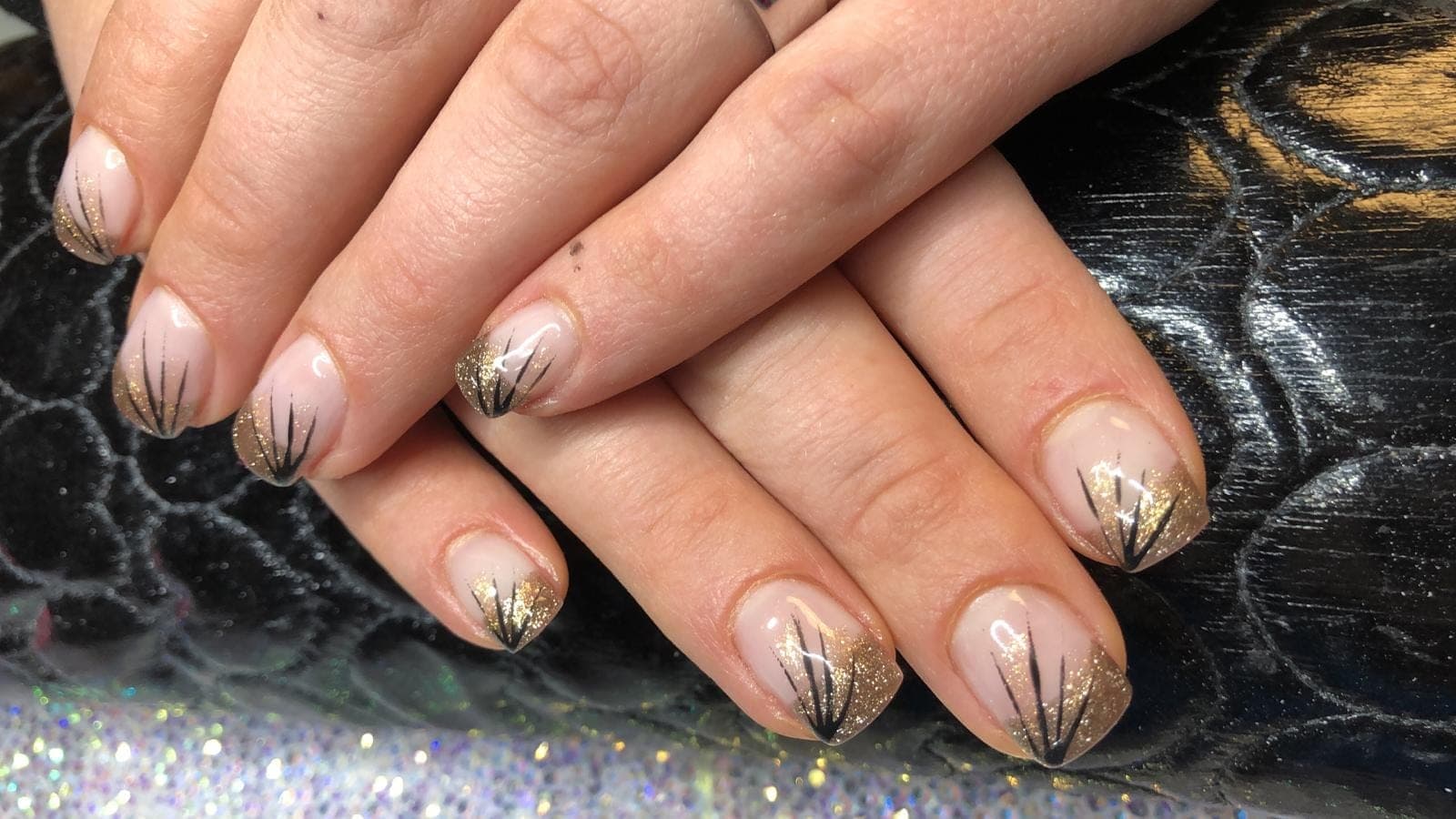Nude-Nägel mit glitzernden Spitzen und feinen schwarzen Linien