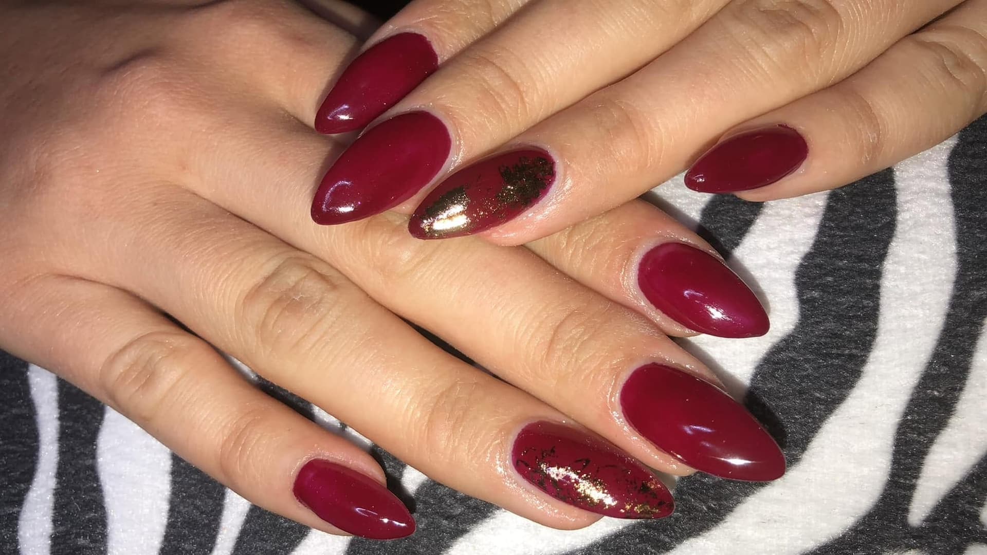 Mandelförmige Nägel in tiefem Weinrot mit goldenem Folien-Akzent, ein Design von Color Queen